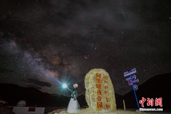 圖為6月20日晚，游客“打卡”西藏阿里暗夜公園，天上是銀河與流星（右上角）。曹枝清 攝