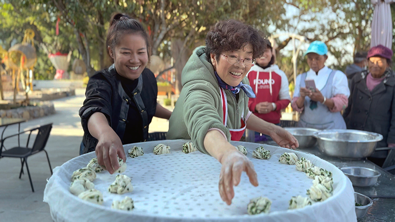 【2】旅居者趙發(fā)英（圖左二）教曼海村村民做花卷。陶思源-攝